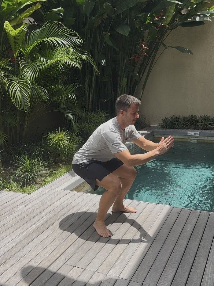 Pablo Berna haciendo una sentadilla sin peso, descalzo, junto a una piscina